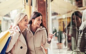 Women in shopping. Two happy women with shopping bags enjoying in shopping, having fun in the city. Consumerism, shopping, lifestyle concept