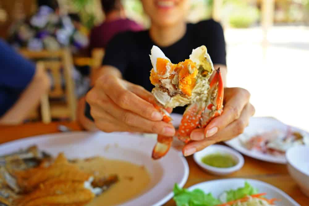 A women enjoying eating Eastern Shore crabs at one of the top Rock Hall MD Restaurants This Summer