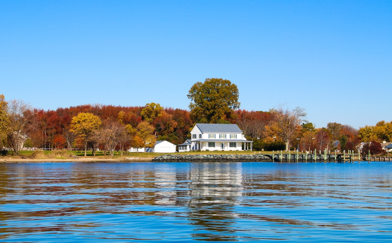 Things to do in Rock Hall MD This Fall 1 Experiencing the fall foliage on the Chesapeake Bay, like this white house surrounded by fall leaves on the trees, is one of the many things to do in Rock Hall MD in the fall.